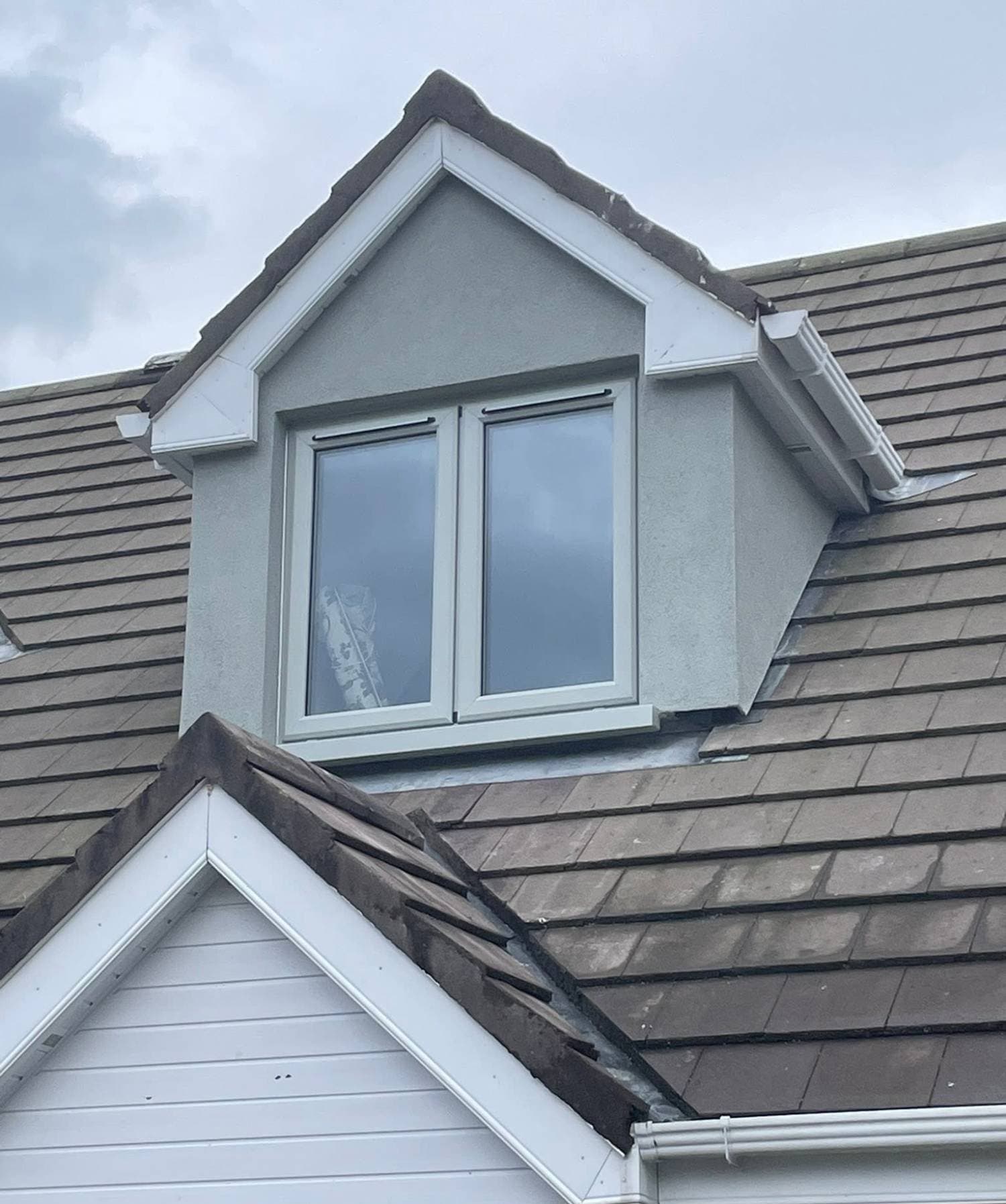 Dormer window with a smooth grey render finish on a tiled roof