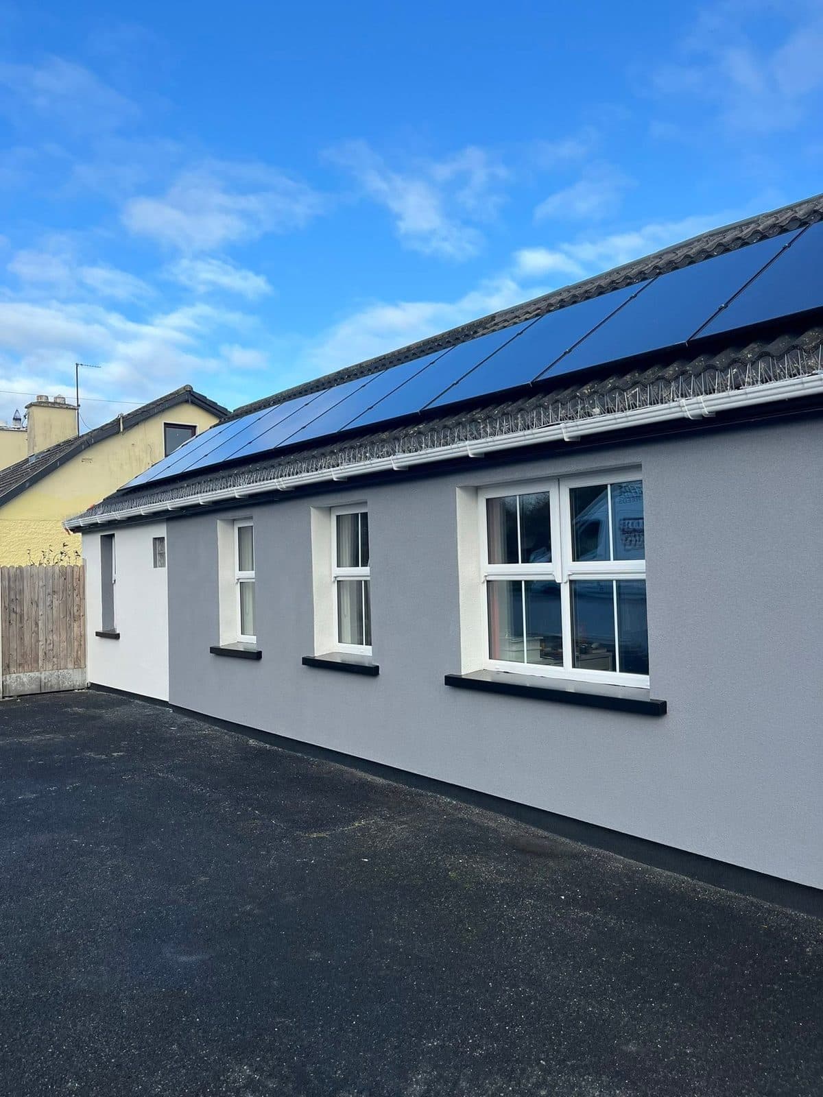 Single-storey house with a fresh grey external render and solar panels on the roof