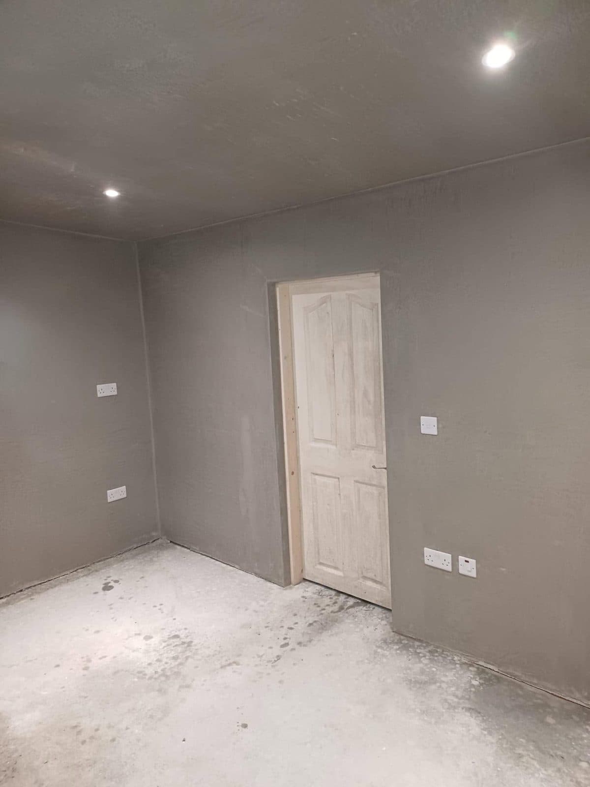Freshly skimmed interior walls and ceiling in a room with a new door